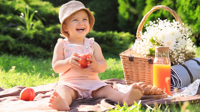 Baby girl outdoors on blanket with peach