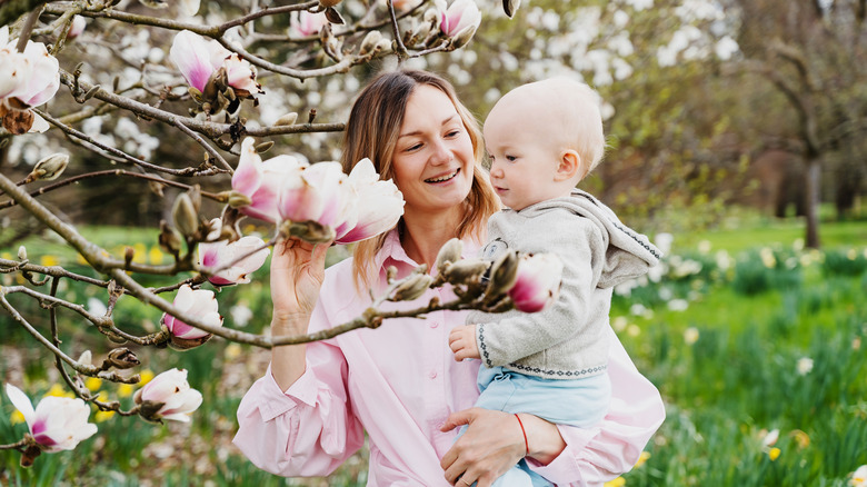 mother and baby looking at magnolia flowers