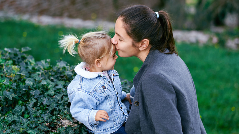 girl and mom sitting on an ivy-covered wall
