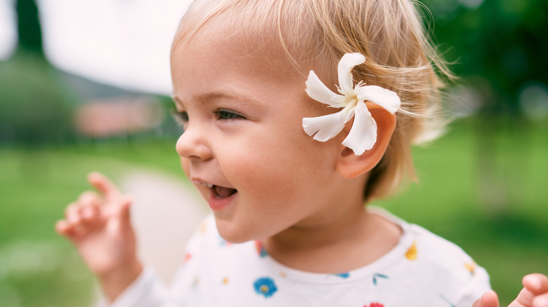 child with a white oleander tucked behind their ear
