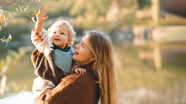 Baby looking at a tree while mom smiles