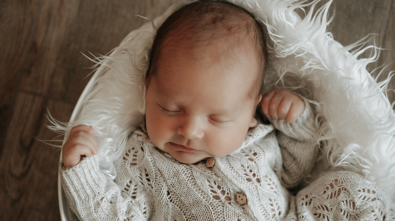 Newborn sleeping in a white, feathery bed