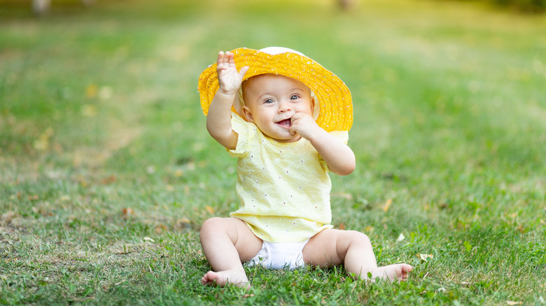 Baby sitting in grass smiling
