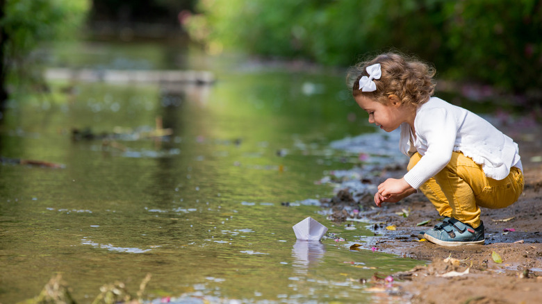 Toddler with bow in hair leaning over stream
