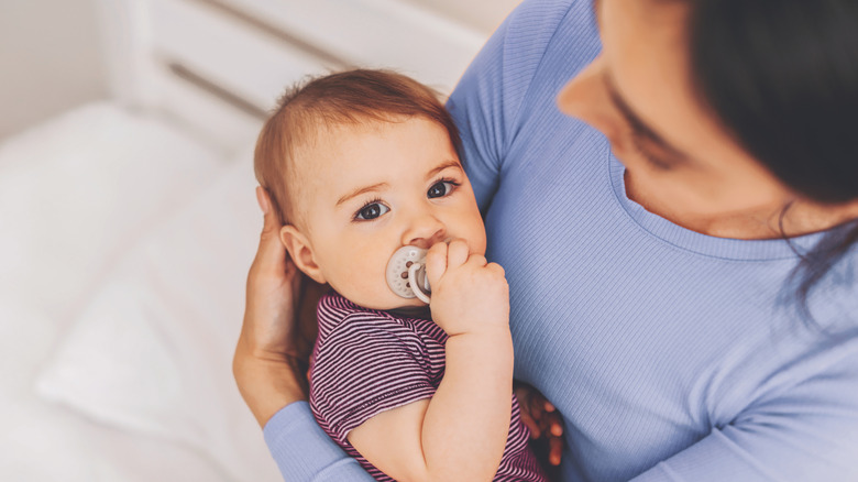 A mother holds her baby boy in her arms as he looks at the camera