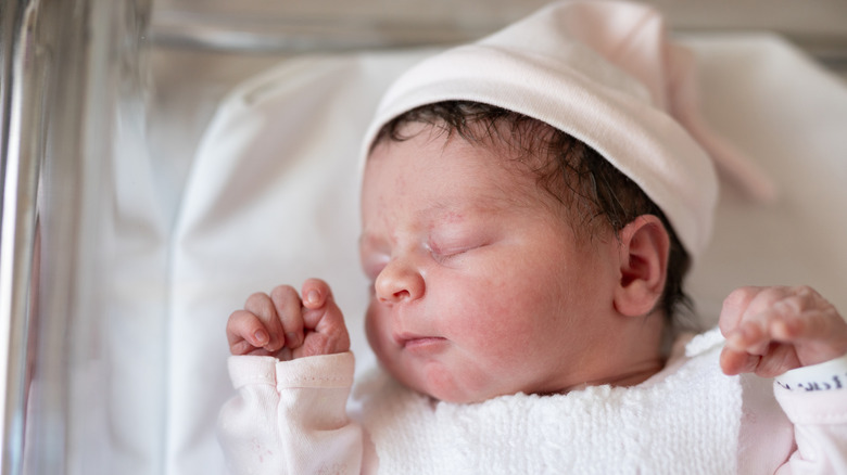 A newborn sleeps in a hospital bassinet