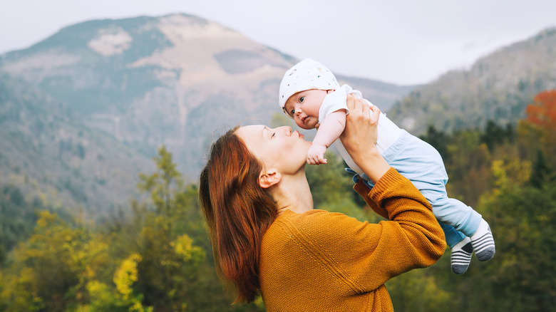 Baby being lifted in front of mountain