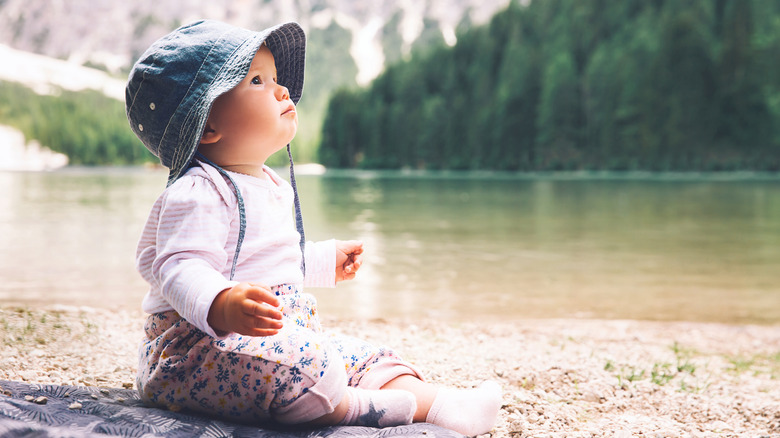 Baby boy looking up with mountains and trees behind him