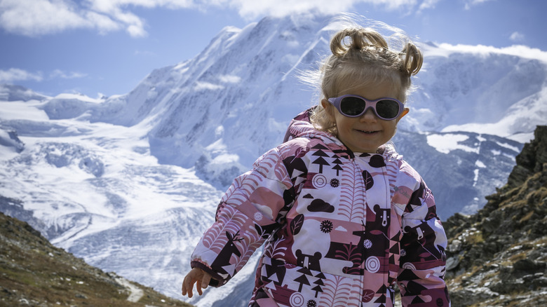 Toddler girl with snowy mountains behind her