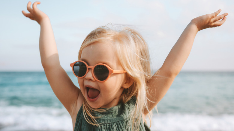 little girl in orange sunglasses at the beach