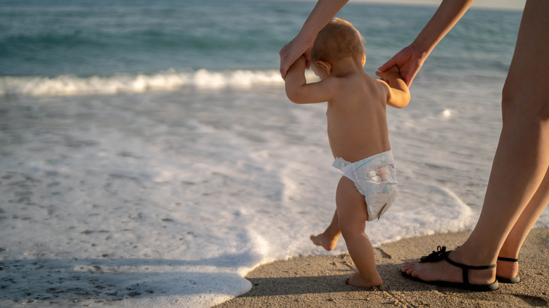 baby playing in the ocean with mom