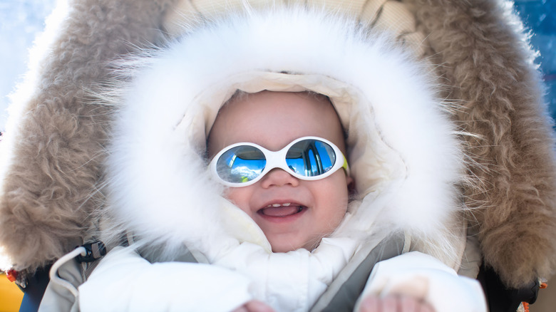 Baby girl in white fur hood with sunglasses on