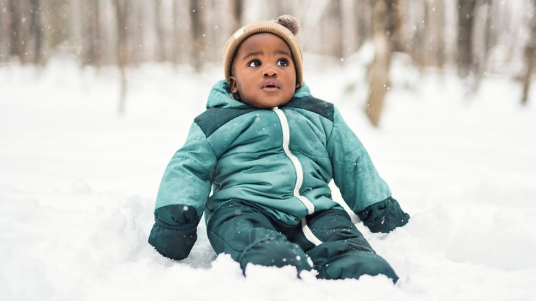 Baby boy in snowsuit sitting in snow