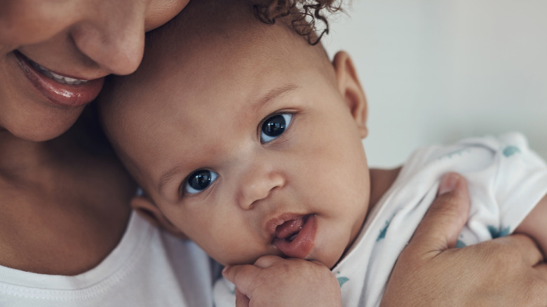 A baby girl is held by her mother against the mother's face