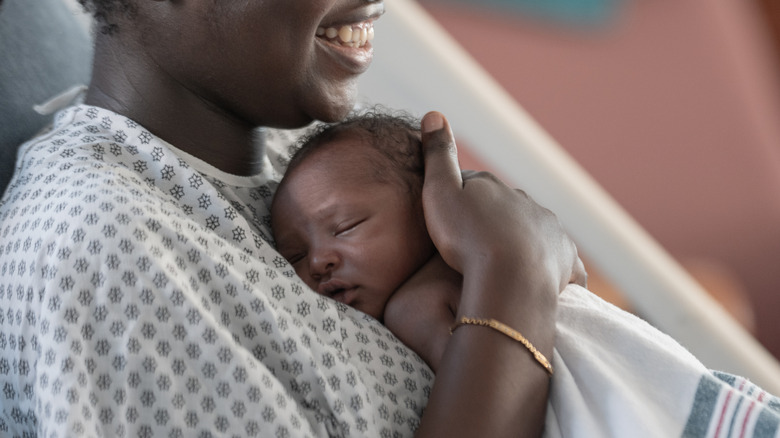 A newborn baby is held against her mother's chest at the hospital