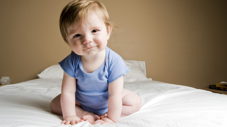 Baby boy sitting up grinning at the camera