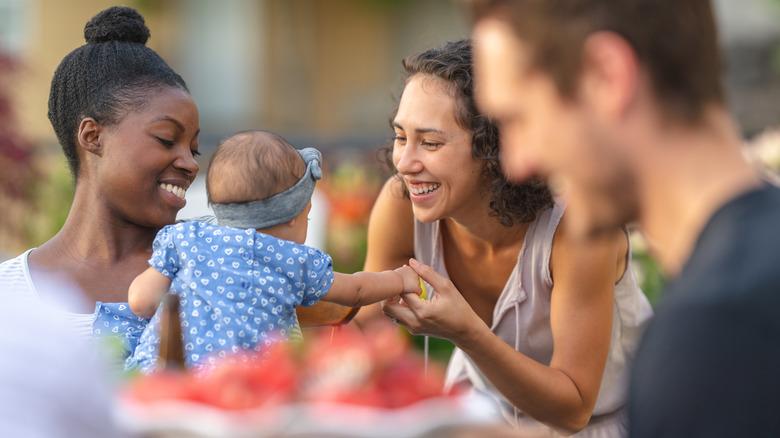 Woman greets a baby held by her mother at a gathering