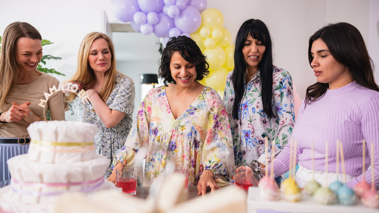 Women at a baby shower participate in a thoughtful activity together