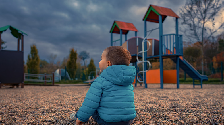 baby sitting on playground with storm clouds approaching