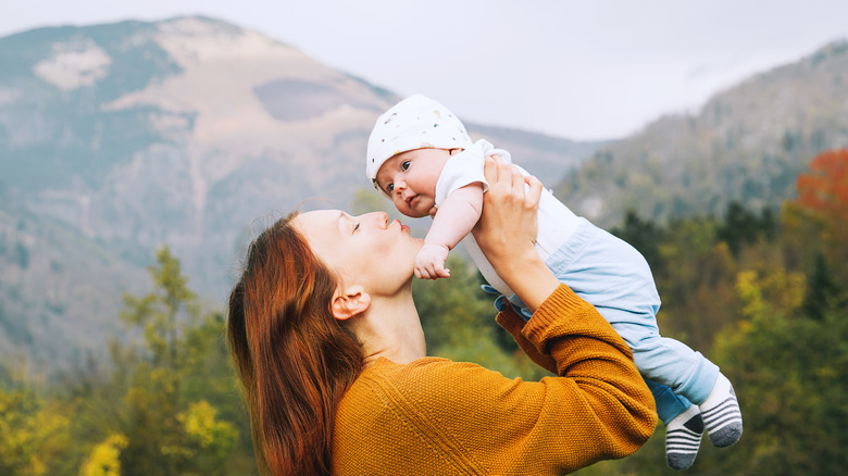 Mother holding up baby with mountains in the background
