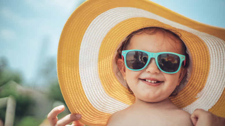 Baby wearing a big yellow sun hat and sunglasses