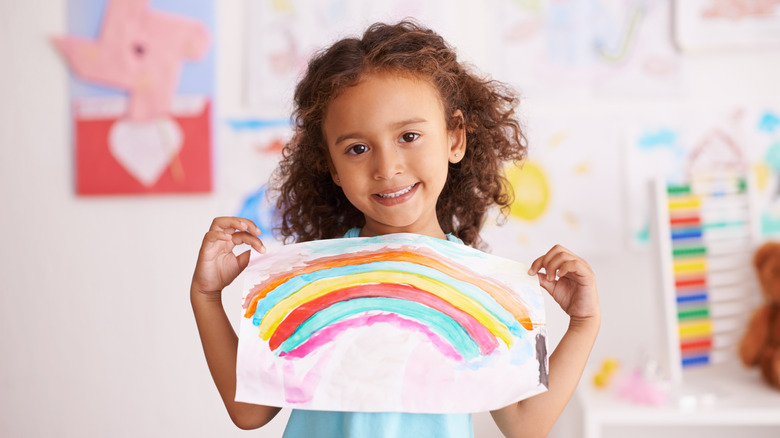 little girl holding a painting with all the colors of the rainbow