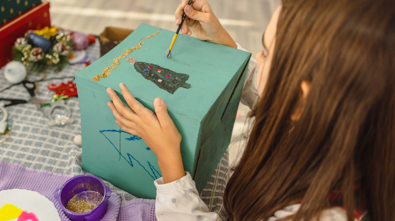 Child decorates a DIY Christmas gift box