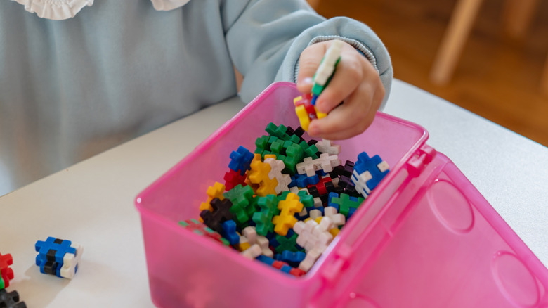A pink wipes container is upcycled into a small toy organizer