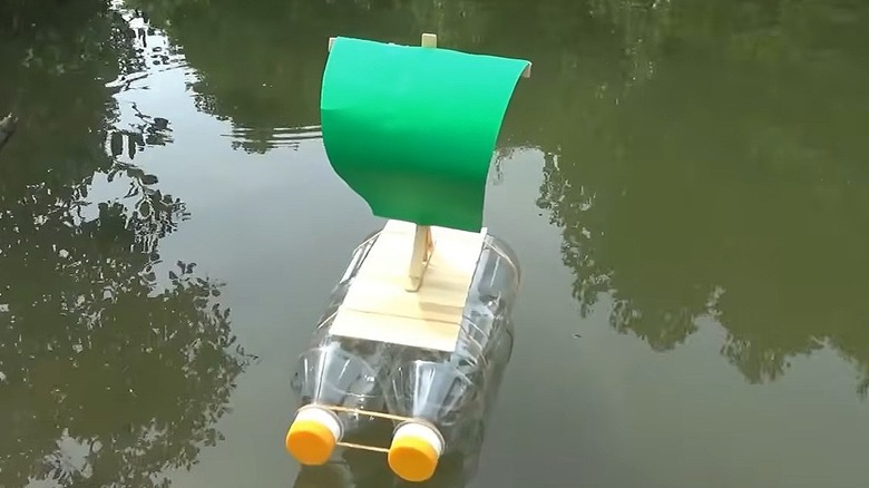 A boat made of two plastic bottles and a wooden base with a paper sail