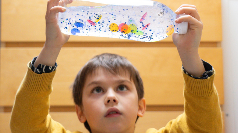 A boy plays with and observes a sensory bottle