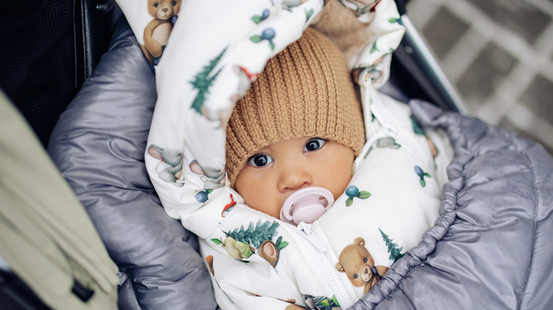 winter baby bundled up with a pacifier and brown hat