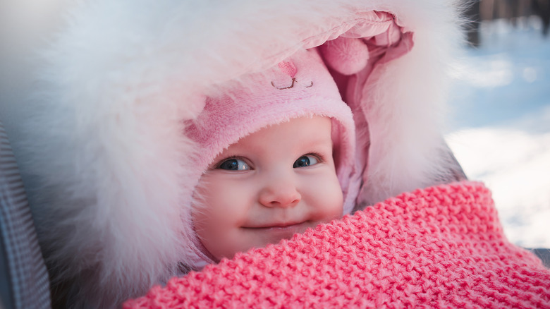 baby girl bundled up in the snow with a pink blanket