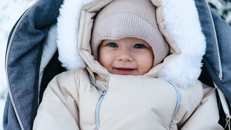 baby boy bundled up during winter in cream clothing in a stroller