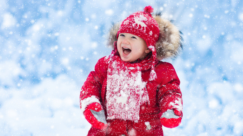child dressed in red laughing in the snow
