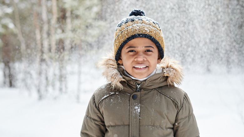 little boy smiling in a snowy forest