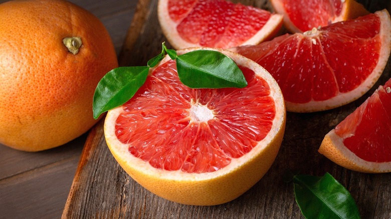 Whole, halved, and quartered grapefruits on a wood serving board