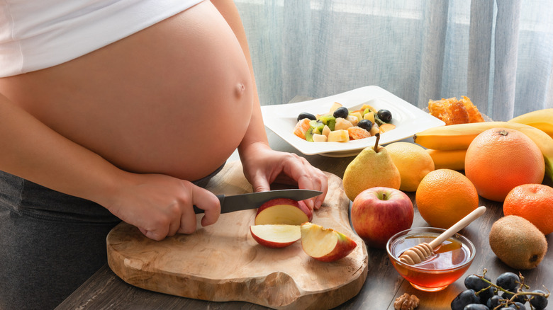 Pregnant person slicing fruit