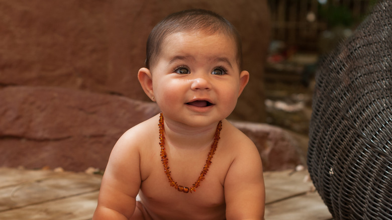baby smiling and wearing an amber necklace