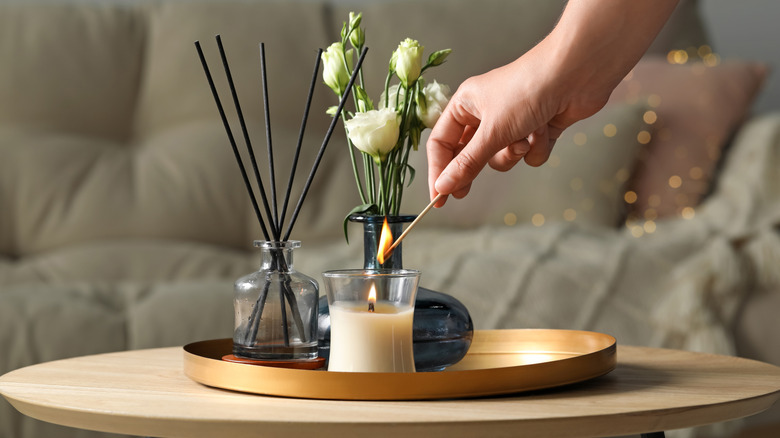 Woman's hand lighting candle on table near sofa