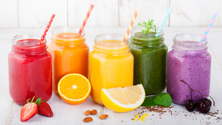 Different colored juices in Mason jars with striped straws