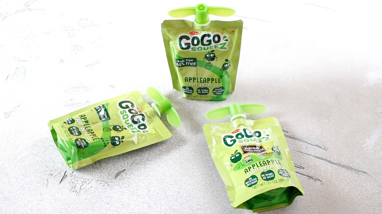 Three GoGo Squeez applesauce pouches on a light gray surface