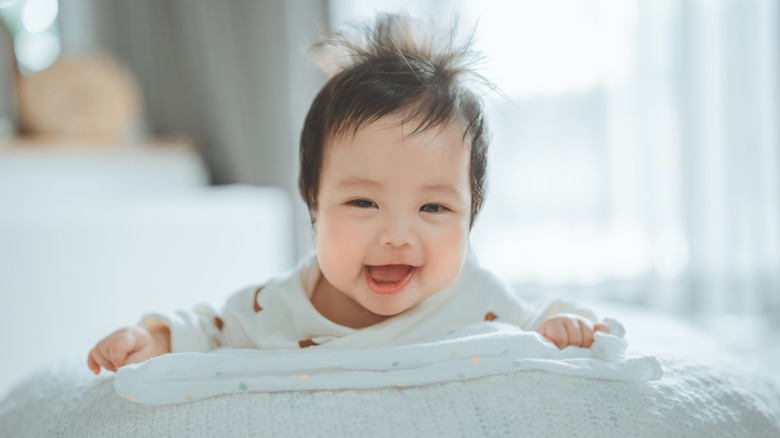 smiling baby on tummy with head of black hair