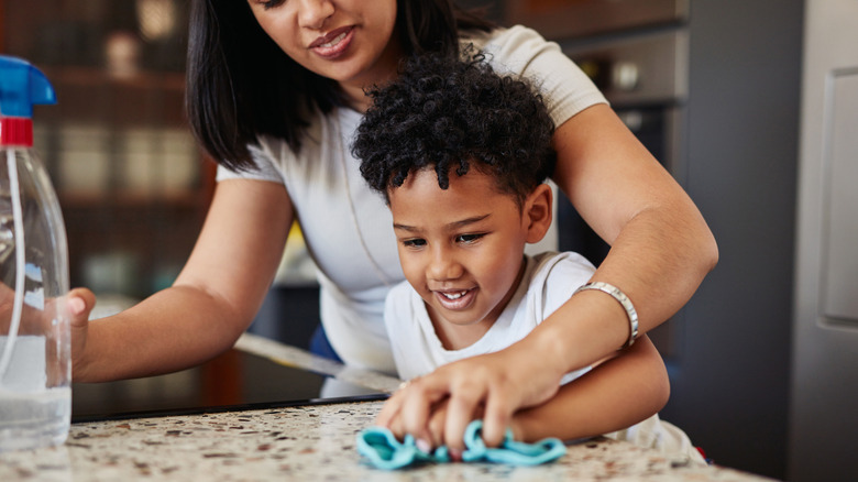 mother and son wiping down kitchen at night