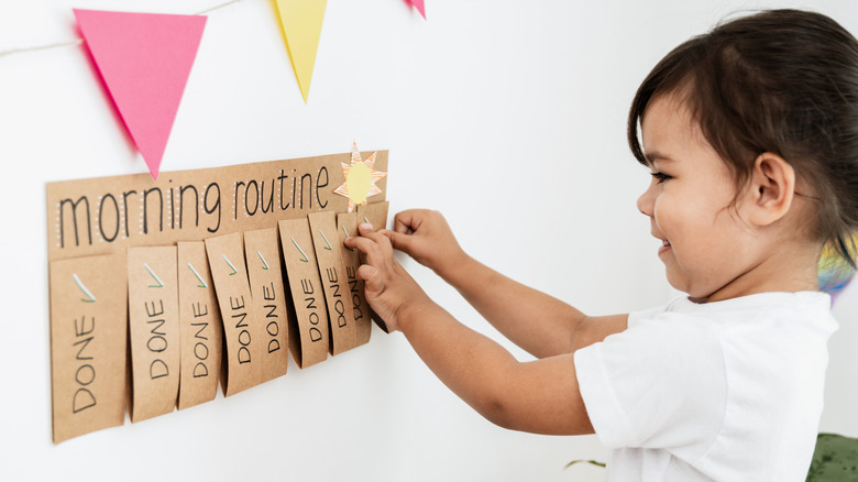 little girl pinning up her chore chart