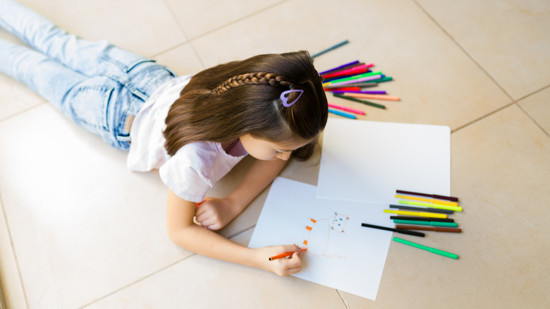 child coloring with markers on a vinyl floor