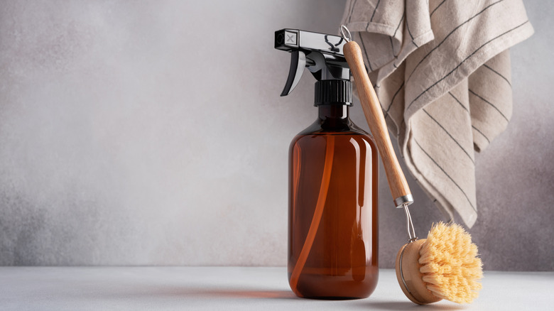 brown glass bottle of cleaning spray with a brush resting on it