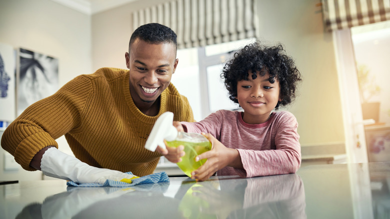 father and child cleaning the kitchen with a homemade cleaner