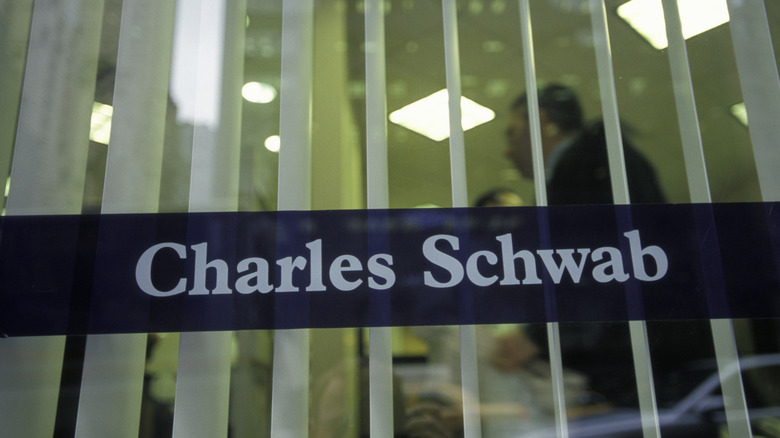 Charles Schwab signage on the window of a building with people visible inside