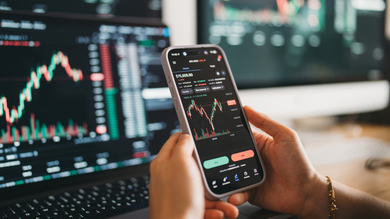 Person using a phone and laptop to review investments and financial data