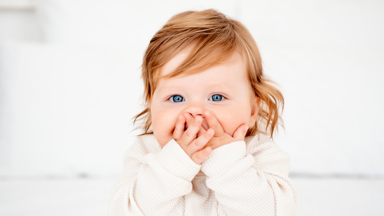 Red-haired baby covering mouth